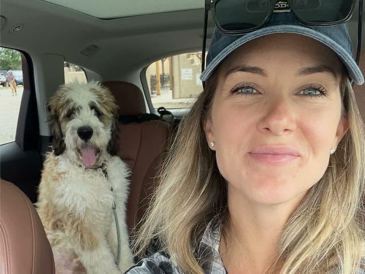 A selfie taken in a car, with a shaggy dog sitting in the back seat